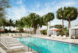 a swimming pool with lounge chairs and palm trees at Residence Inn by Marriott Miami Beach Surfside in Miami Beach