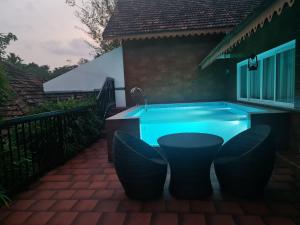 a hot tub with chairs in front of a house at Athirapally Green Trees in Athirappilly