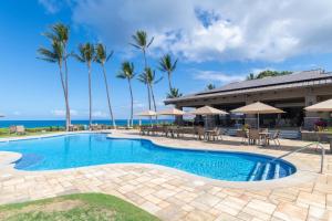 a swimming pool with tables and chairs and palm trees at Wailea Ekahi 24B in Wailea