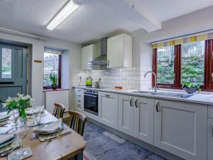 a kitchen with white cabinets and a wooden table with a dining room at 2 Bed in Wedmore 82378 in Theale