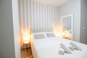a white bedroom with a white bed and two lamps at Suite Parque del Turia by Clink in Valencia