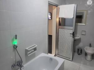 a white bathroom with a shower and a sink at Hôtel particulier HP in Conakry