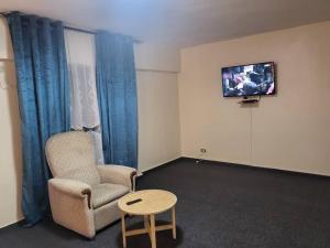 Habitación con silla y TV en la pared. en Hôtel particulier HP en Conakry