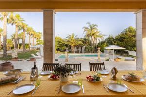 Una mesa con platos y utensilios sobre ella con una piscina. en Villa Alike - IsulaTravel, en Módica