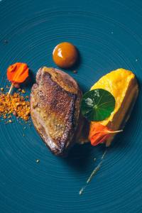 um prato azul com um pedaço de carne e uma laranja em Villa de l'Etang Blanc em Seignosse