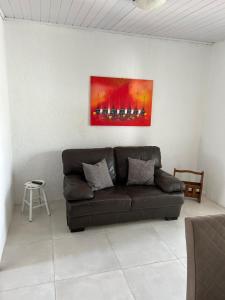 un sofá en una sala de estar con una pintura en la pared en Recanto do Sul - Campeche, en Florianópolis