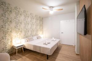 a bedroom with a white bed and a tv at Suite Parque del Turia by Clink in Valencia