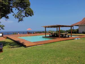 een zwembad met een houten terras en een picknicktafel bij 180° Ocean View Dune House in Chefe Imala