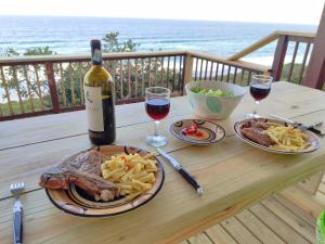een tafel met een fles wijn en een bord eten bij 180° Ocean View Dune House in Chefe Imala