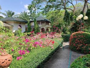 a garden with flowers in front of a house at Ekman Garden Resort in Sichon