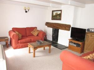 a living room with a red couch and a fireplace at Jowders Cottage in Marazion