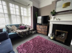 sala de estar con sofá azul y chimenea en For contractors nr Worthing station large 4 bed 2bath house sleeps 10 by Eagle Owl Property, en Worthing