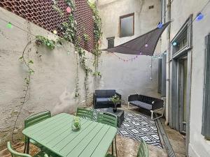 a patio with a green table and chairs and an umbrella at La terrasse des remparts - Sublime T3 in Carcassonne