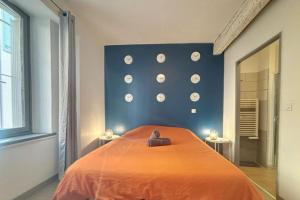 a bedroom with an orange bed and a wall with clocks at La terrasse des remparts - Sublime T3 in Carcassonne