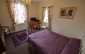 a bedroom with a purple bed and two windows at Lime Stays in Derby