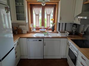 a kitchen with white cabinets and a sink and a window at Casa Camino Santiago-Fisterra in Amés