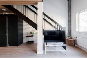 a living room with a black couch and stairs at 2ndhomes Tampere "Pyynikki" Top Floor Loft Apartment in Tampere