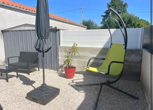 einen Stuhl und einen Regenschirm auf einer Terrasse in der Unterkunft Maison indépendante parfaite pour tous voyageurs. in Le Landreau