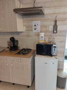 eine Küche mit einer Mikrowelle auf dem Kühlschrank in der Unterkunft Maison indépendante parfaite pour tous voyageurs. in Le Landreau