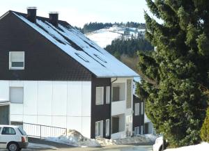 a building with a snow covered roof next to a tree at Vakantiehuisje Winterberg in Winterberg