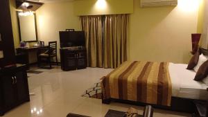 a bedroom with a bed and a desk and a television at Hotel Pushpak in Bhubaneshwar