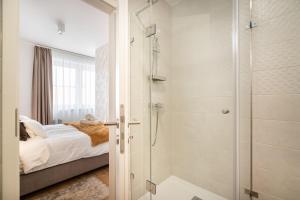 a bathroom with a shower and a bed with a glass door at The Rose Garden Apartments in Budapest