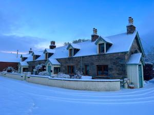 een huis bedekt met sneeuw met een hek bij Rosemount Cottage ONE- Highland Cottage in Garve