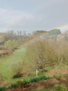 a view of a field with a rainbow in the distance at Maison de campagne in Le Lude