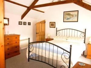 Jowders Cottage في مرزيون: غرفة نوم بسرير أسود وخزانة خشبية