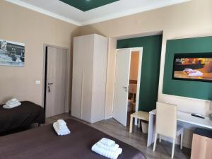 Habitación con cama, escritorio y TV. en Prestige B&B, en Catania