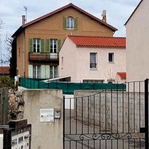 a house with a fence in front of a building at La maison de Dannie in Gardanne