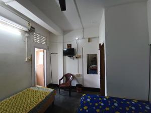 1 dormitorio con 1 cama y 1 silla en una habitación en Ajanta Lodge, en Guwahati