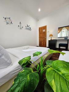 een slaapkamer met een bed met een plant ernaast bij Little Heaven by Sky Hive, A Beach Front Bungalow in Tanjung Bungah