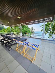 een picknicktafel en stoelen op een patio met uitzicht op de oceaan bij Little Heaven by Sky Hive, A Beach Front Bungalow in Tanjung Bungah