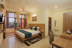 a bedroom with a bed and a table and a desk at Hotel Lemon Suites in Noida