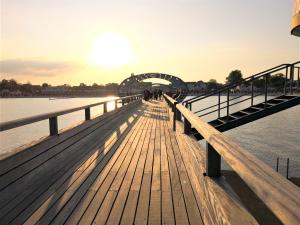 a wooden pier with the sun setting over the water at FeWo Sol Mare Whg2 in Kellenhusen