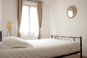 a white bedroom with a bed and a window at *Claire : Appartement avec *balcon + parking* in Mantes-la-Jolie