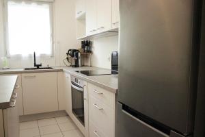 a kitchen with white cabinets and a gray refrigerator at *Claire : Appartement avec *balcon + parking* in Mantes-la-Jolie