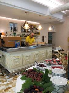 Ein Mann, der hinter einer Theke mit Teller voller Essen steht. in der Unterkunft Hotel Lazzarini in Bellaria-Igea Marina