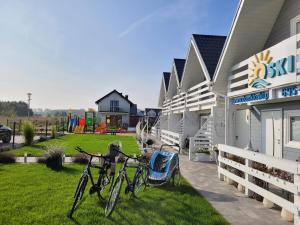 twee fietsen geparkeerd buiten een huis met een speeltuin bij Domki Oski in Sarbinowo