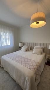a bedroom with a large white bed and a light fixture at Sunset Cabedelo Residence - Heated Pool in Viana do Castelo