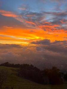 a sunset over a field with a fence on a hill at En las Nubes in Medellín