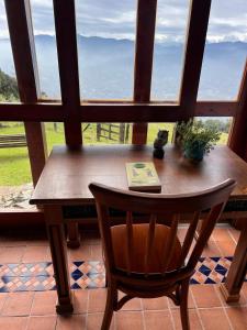 a table with a book and a chair in front of a window at En las Nubes in Medellín