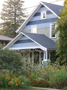 een huis met een blauw dak en wat bloemen bij Garden Guesthouse in Viroqua