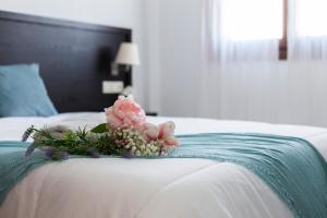 a bouquet of flowers sitting on top of a bed at Ático Lux Sevilla Nuevo Bormujos in Bormujos