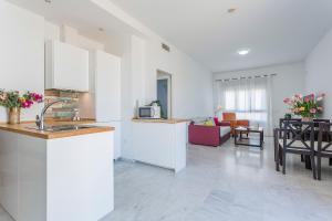 a kitchen with white cabinets and a living room at Ático Lux Sevilla Nuevo Bormujos in Bormujos