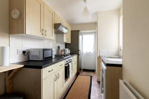 a small kitchen with white cabinets and a microwave at The Heart of Crawley in Crawley