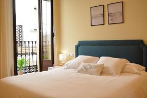 um quarto com uma cama com almofadas brancas e uma varanda em APARTAMENTO PUERTA DE CÓRDOBA- Exterior con balcones em Córdoba