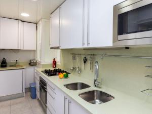 een witte keuken met een wastafel en een magnetron bij Apartment Sants-Montjuic Rambla Badal by Interhome in Barcelona