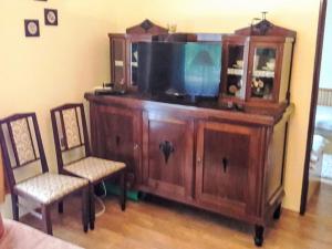 a wooden entertainment center with a tv and two chairs at Holiday Home Baracka by Interhome in Trenčianske Teplice